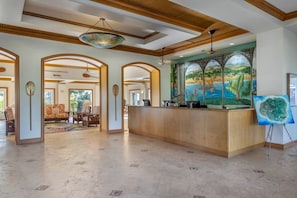 A spacious lobby with a reception desk, arched doorways, and a mural of a tropical landscape. - Spend Thanksgiving 2026 in Paradise! 2BR/2BA condo at The Point at Poipu (Koloa)