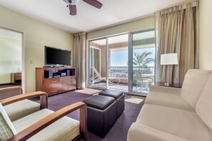 A hotel room with a balcony, a flat-screen TV, a sofa, a coffee table, and a wooden cabinet. - Spend Thanksgiving 2026 in Paradise! 2BR/2BA condo at The Point at Poipu (Koloa)