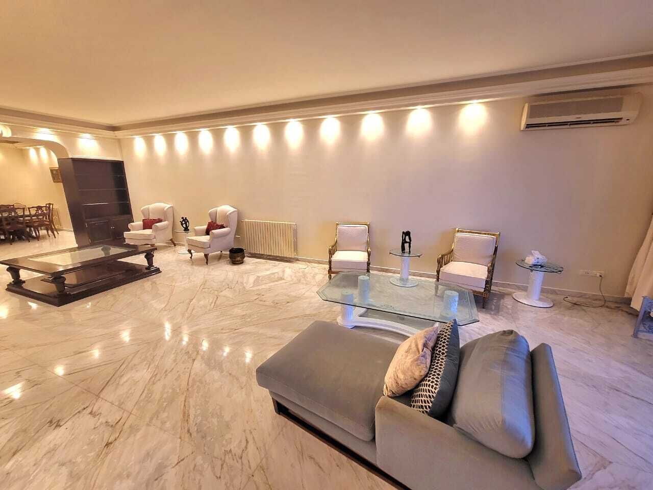A modern living room with a marble floor, a grey sofa, and a glass coffee table.