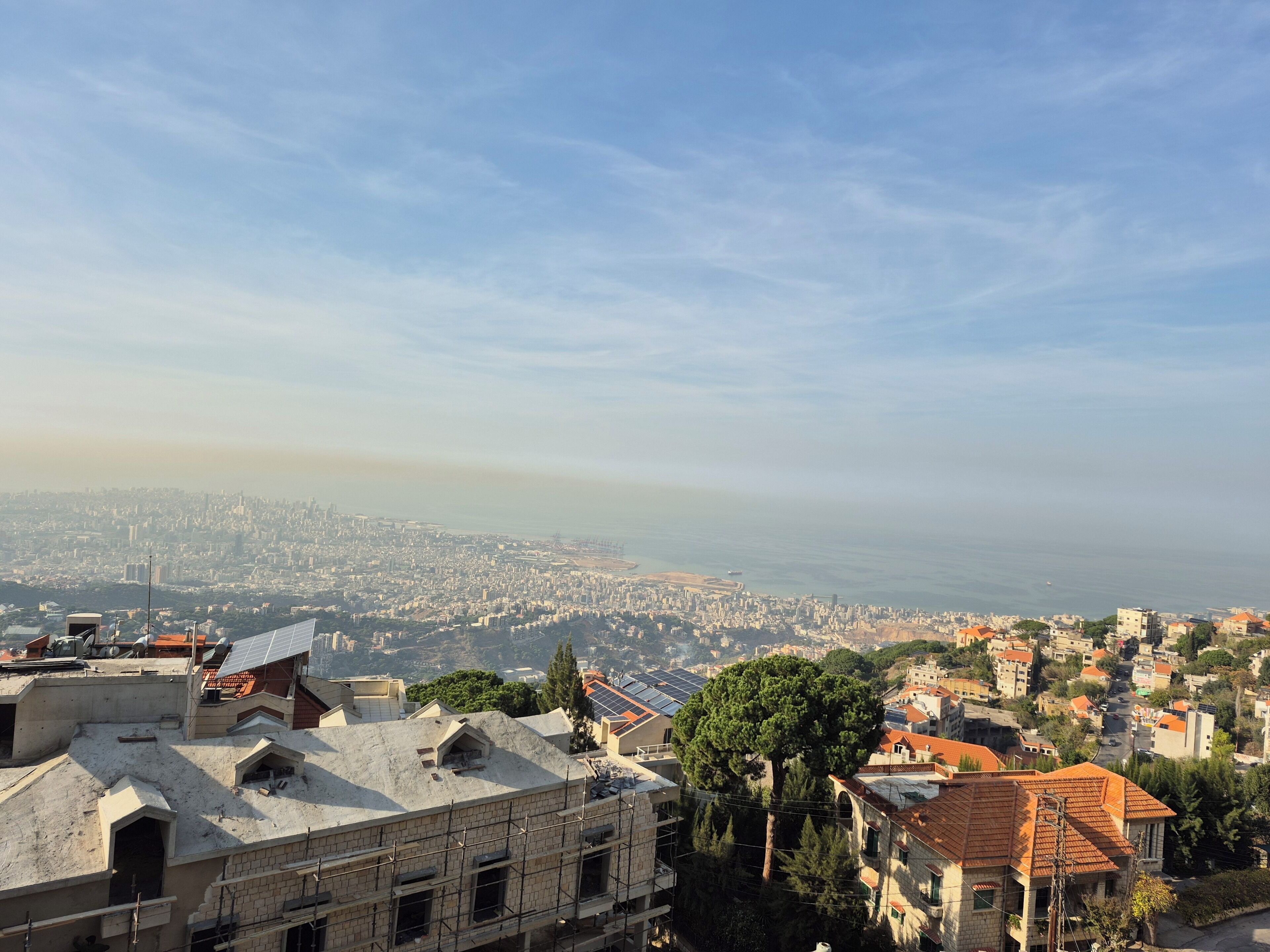 Un paisaje urbano con edificios, cielo despejado y una vista distante del mar.