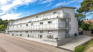 Un edificio de varios pisos con balcones, una escalera y una fila de buzones.