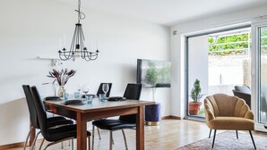 Un comedor moderno con una mesa de madera, sillas negras y una araña.