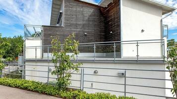 A modern building with a flat roof, a large window, and a metal railing.