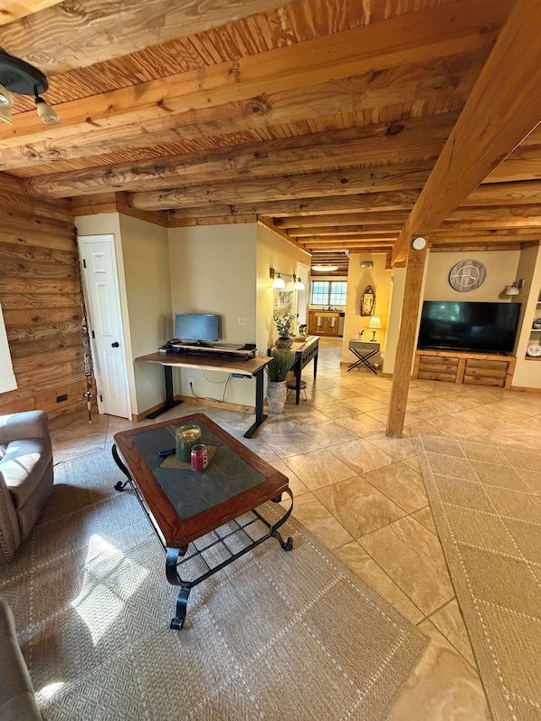 A cozy living room with a wooden ceiling, a television, a coffee table, and a sofa.