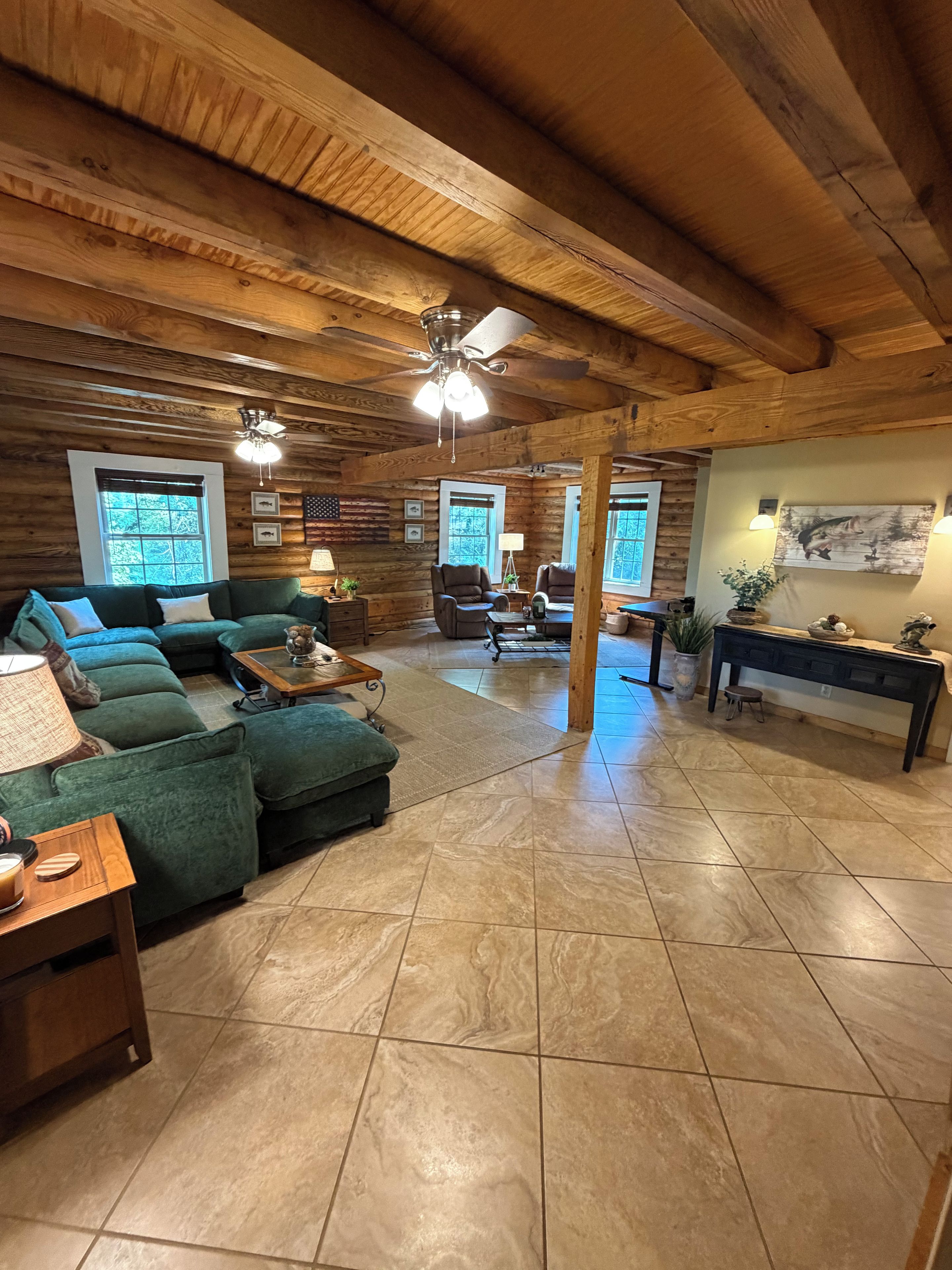 A log cabin interior with a sectional sofa, a coffee table, and a fireplace.