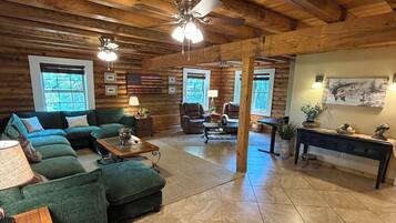 A log cabin interior with a sectional sofa, a coffee table, and a fireplace.