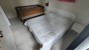 A bedroom with a bed, a nightstand, and a wall-mounted artwork. - SHB Riviera Dreams com Piscina e Sauna  (Bertioga)