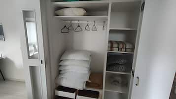 A white closet with shelves, hanging space, and a folded clothes rack.