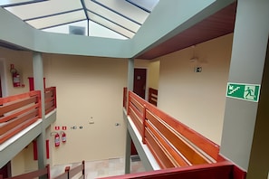 A multi-level interior with a central staircase, fire safety equipment, and emergency exit signage. - SHB Riviera Dreams com Piscina e Sauna  (Bertioga)