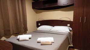 A hotel room with a bed, two towels, a wooden headboard, a wooden wardrobe, and a curtain. - real village roma (Roma)