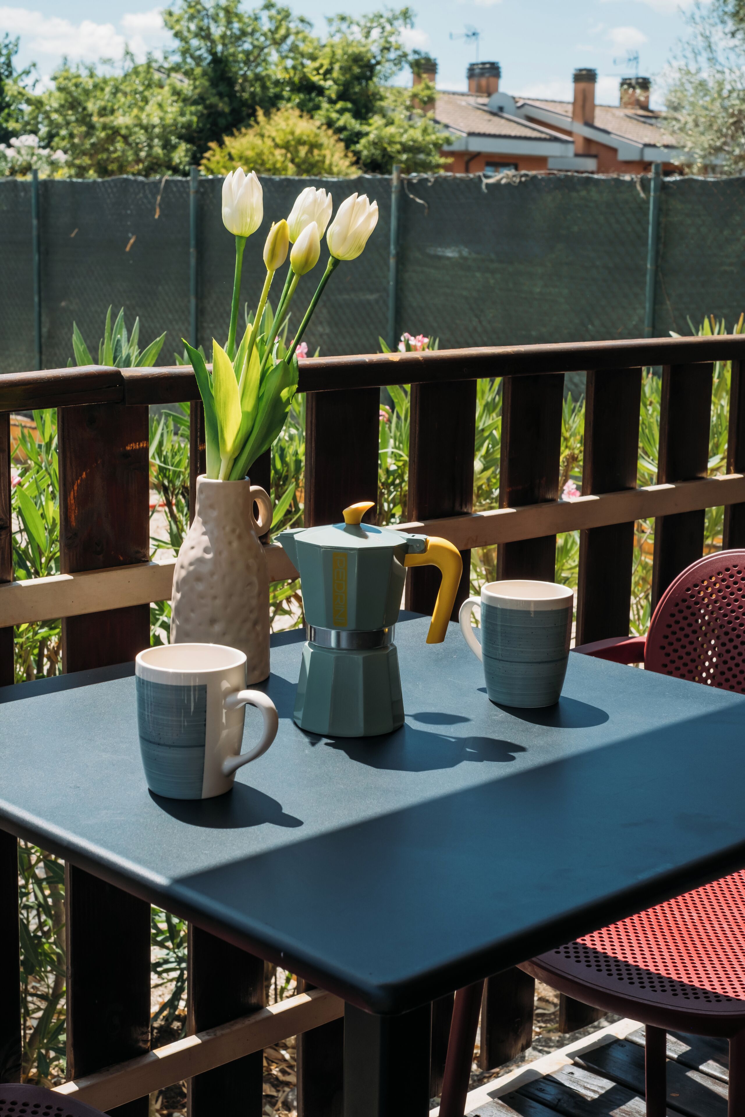 Ett bord med en kaffebryggare, en mugg och en vas med blommor.