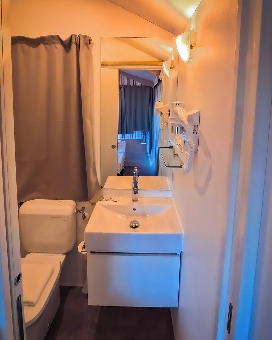 A compact bathroom with a toilet, sink, and shower area.