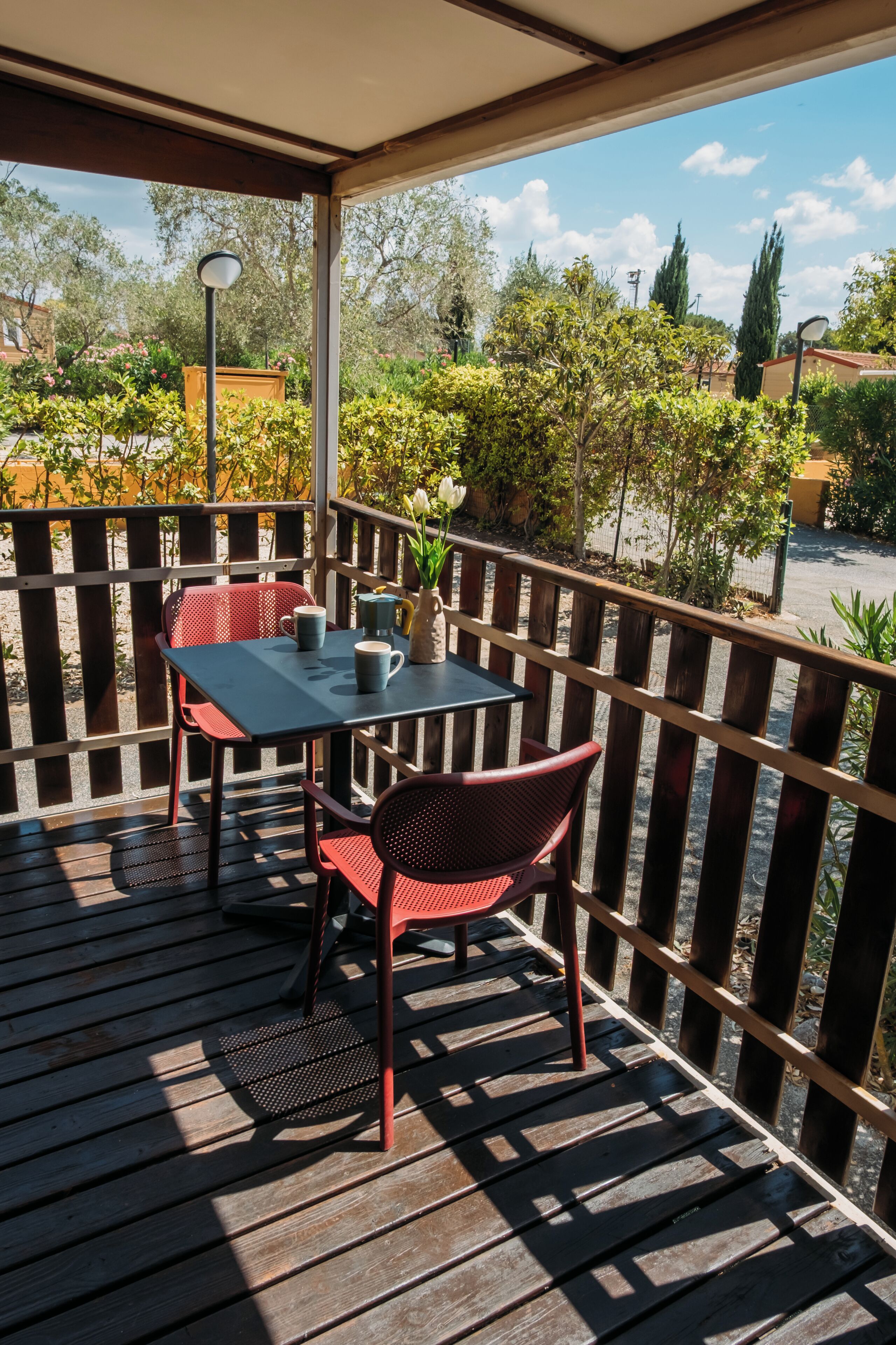 Um pátio externo com mesa e cadeiras, cercado por uma vedação de madeira e vegetação.