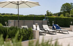 Ein Außenbereich mit Lounge-Möbeln, einem großen Sonnenschirm und einem Wandheizgerät.