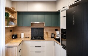 Eine moderne Küche mit einem schwarzen Kühlschrank, einem Herd und einer Kaffeemaschine.