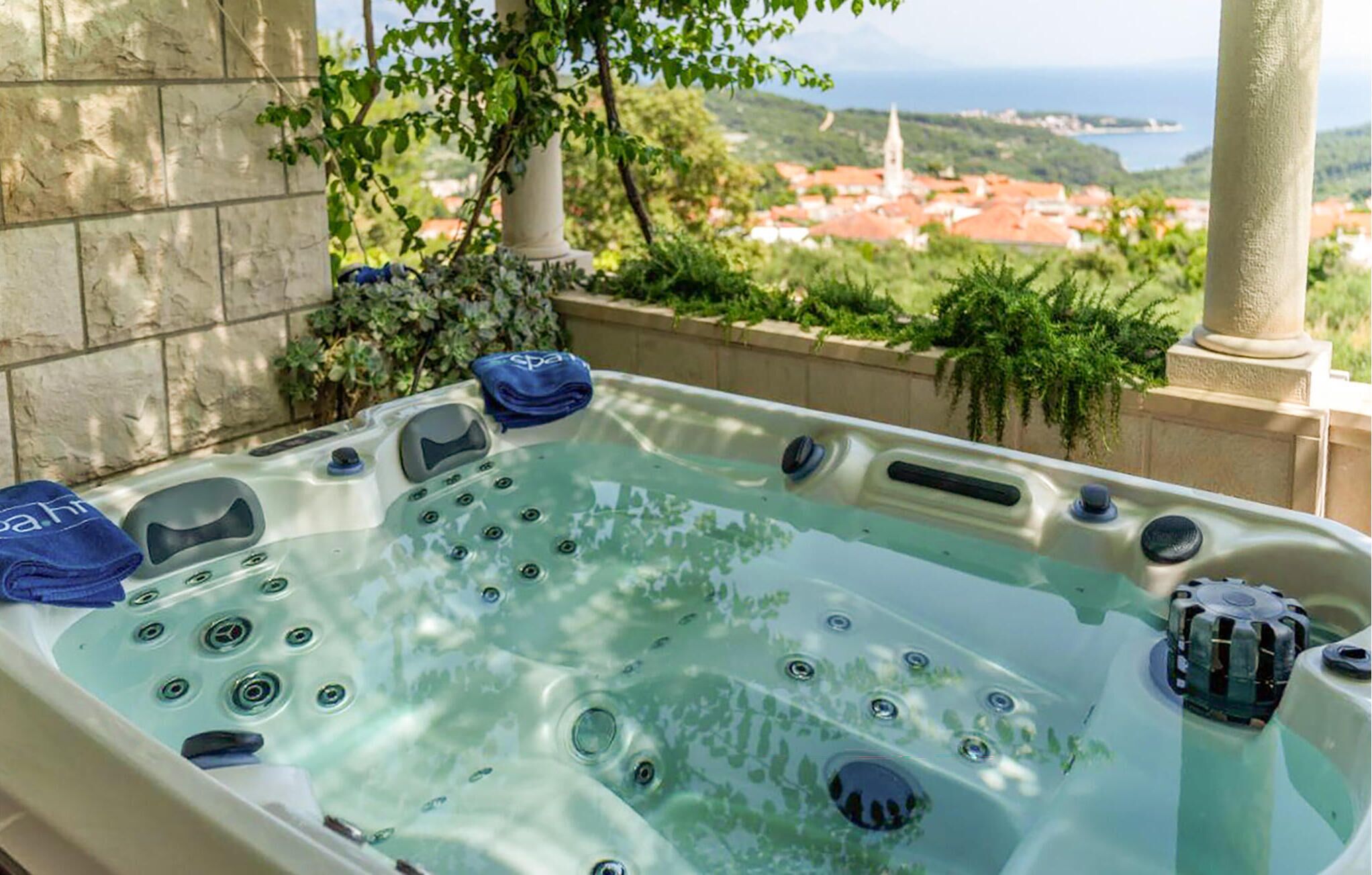 Ein Whirlpool mit zahlreichen Düsen, vor einer malerischen Kulisse aus Gebäuden und Grünflächen.