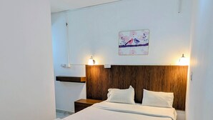 Una habitación de hotel moderna con una cama grande, cabecero de madera, dos lámparas de noche y una obra de arte colgada en la pared.