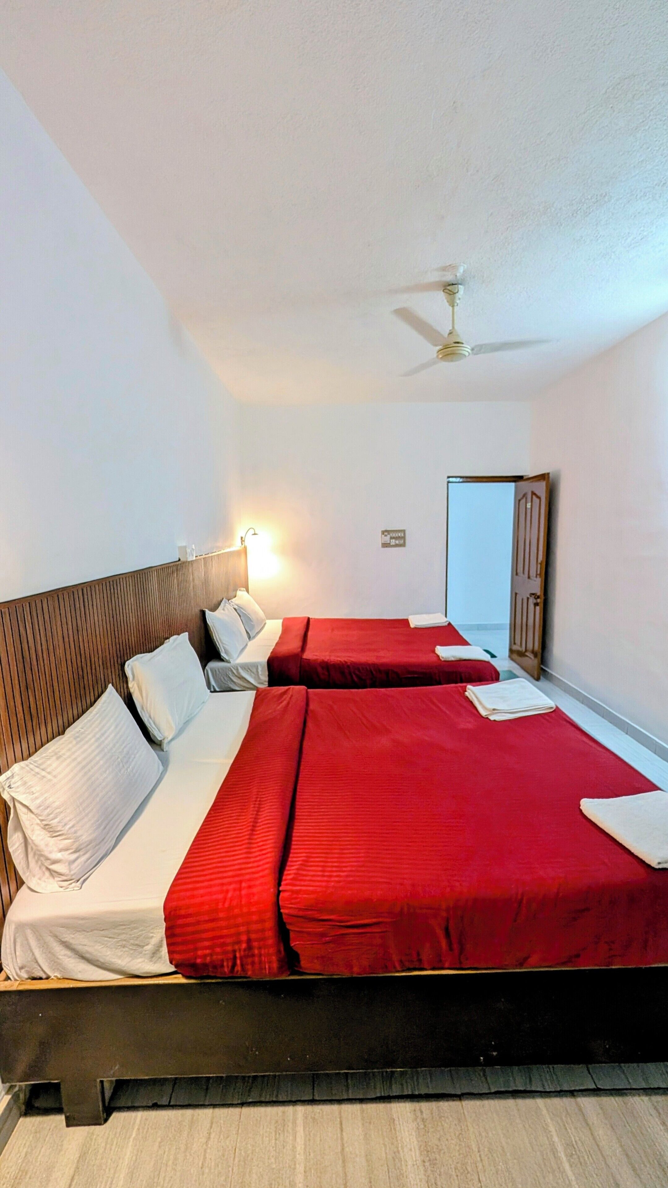 Habitación de hotel con dos camas, un ventilador de techo y una puerta.