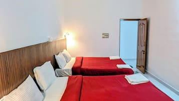 Habitación de hotel con dos camas, un ventilador de techo y una puerta.