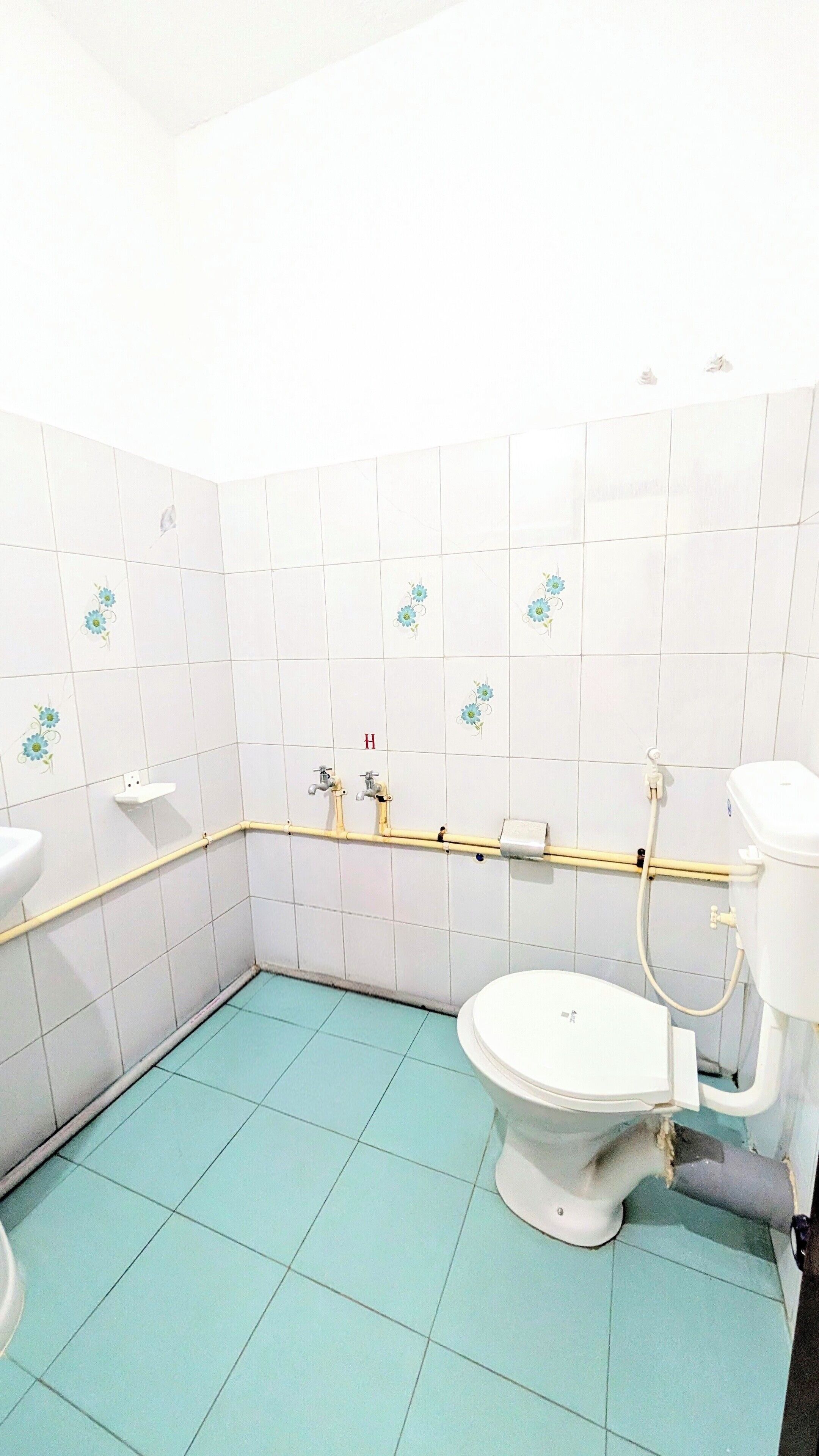 Un baño con azulejos blancos, inodoro, lavabo y zona de ducha.