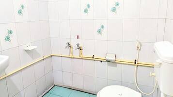 Un baño con azulejos blancos, inodoro, lavabo y zona de ducha.
