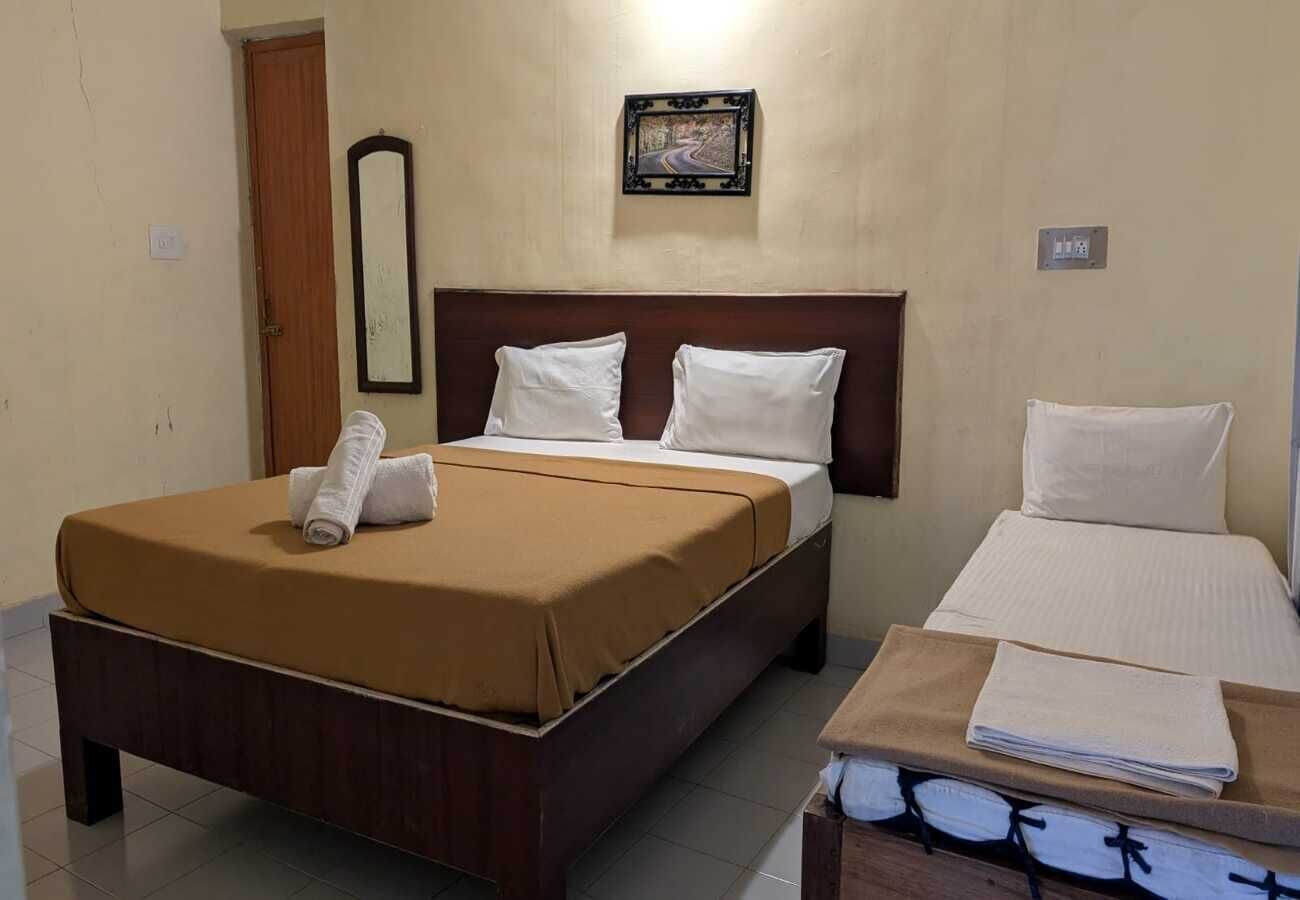 Habitación de hotel con cama, mesita de noche, espejo y un cuadro en la pared.