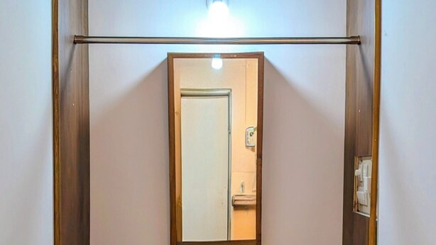 Una habitación con un armario de madera, un espejo y una lámpara sobre el espejo.