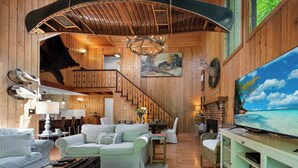 Un salón espacioso con techo alto, chimenea, televisor y comedor.