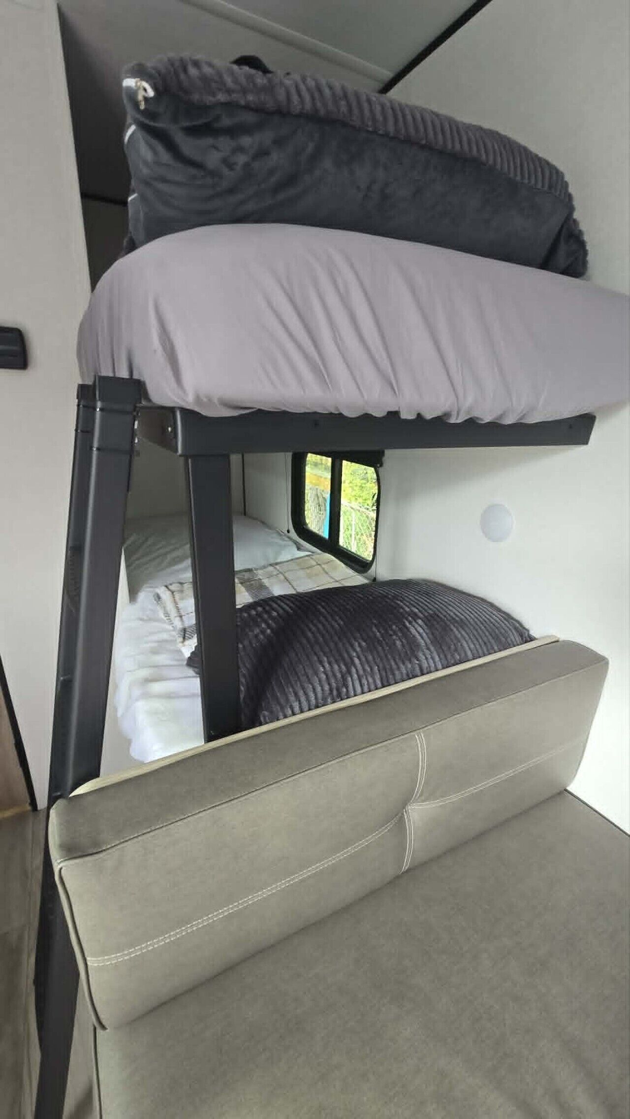 A bunk bed with a window, a sofa, and a small table.