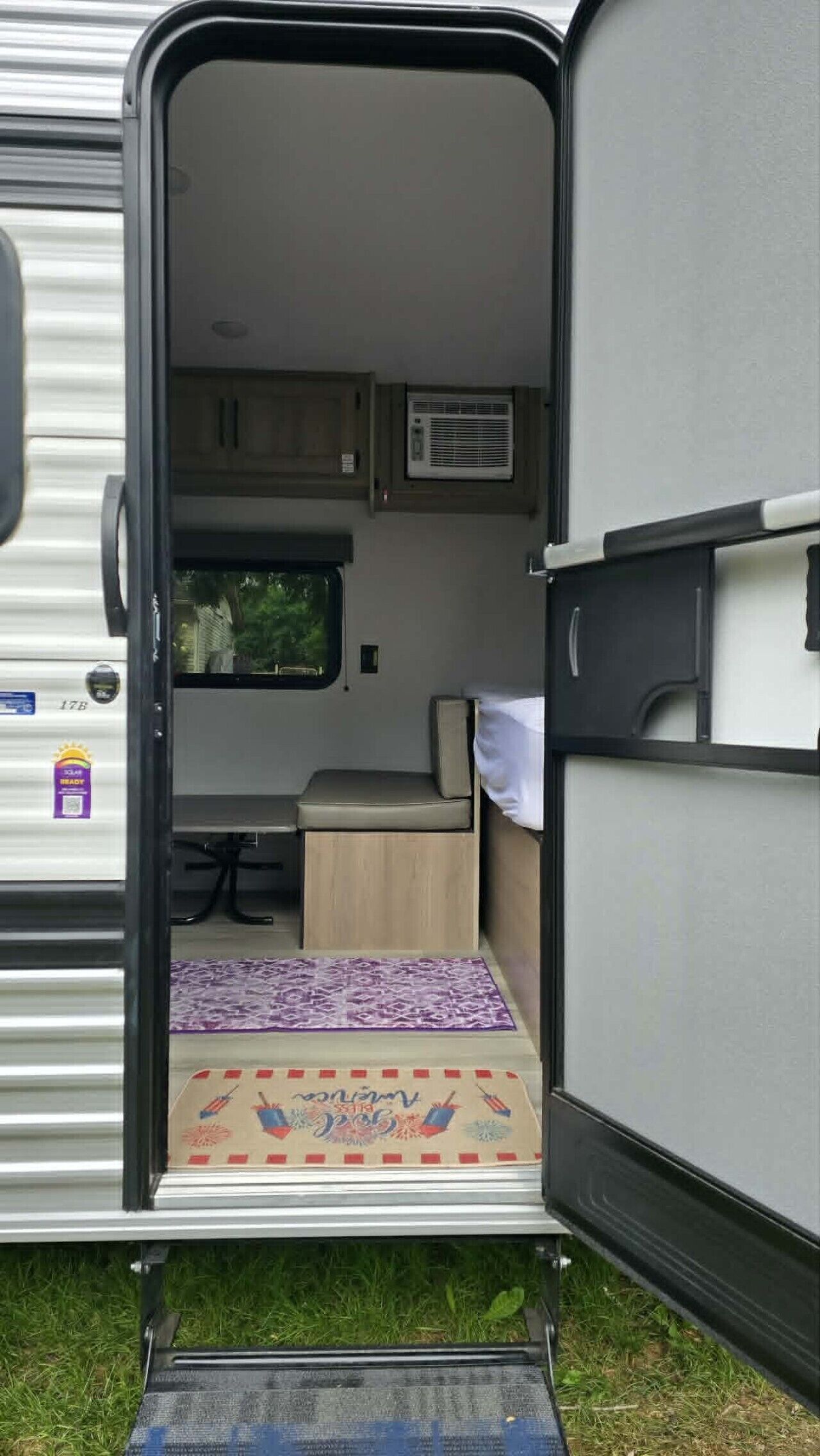 A travel trailer interior with a kitchenette, a small dining area, and a sleeping berth.