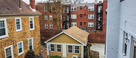 Un quartier résidentiel avec une petite maison au premier plan, entourée d’immeubles en briques plus hauts.