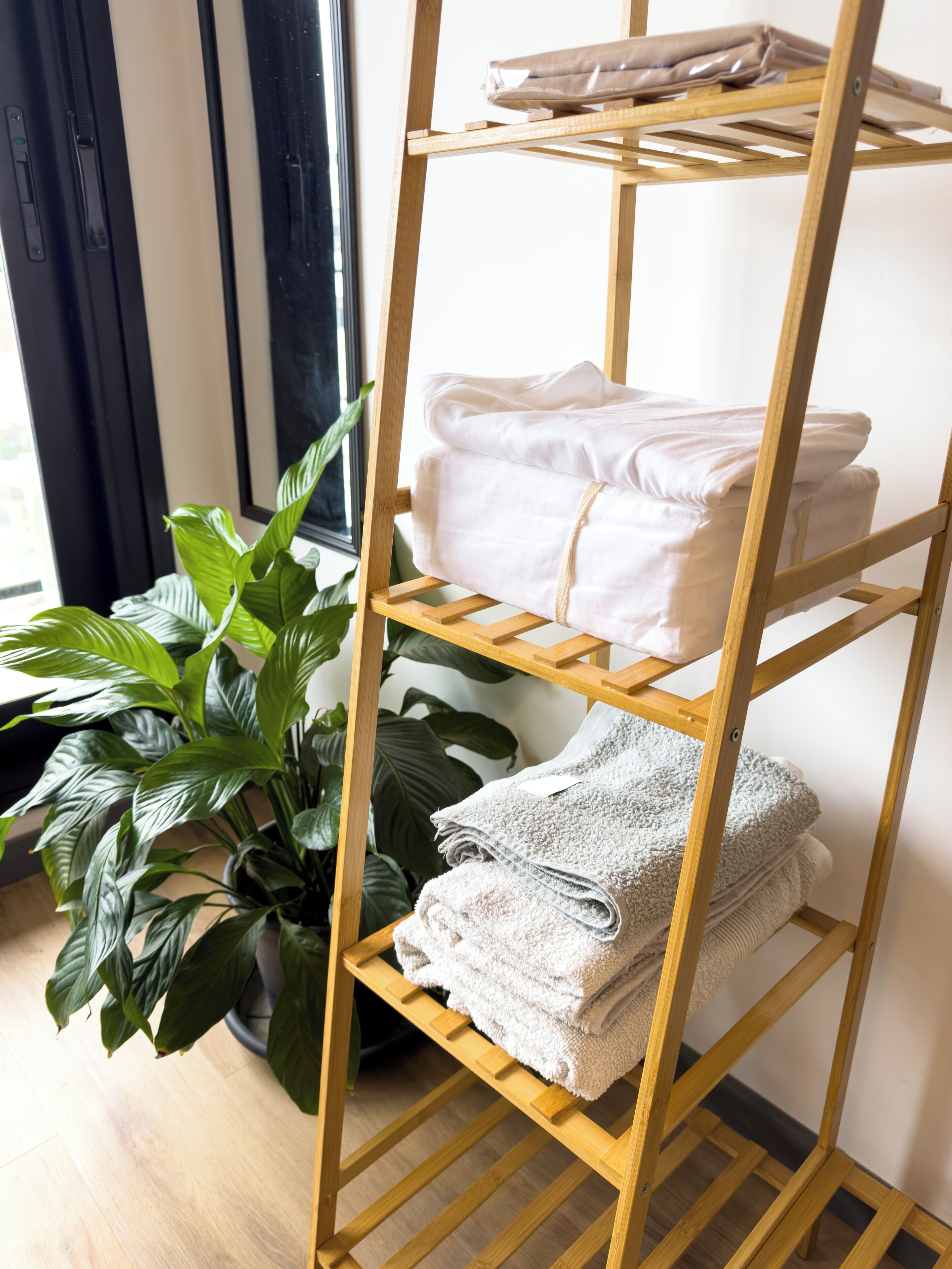 A wooden shelf with folded towels and a potted plant.