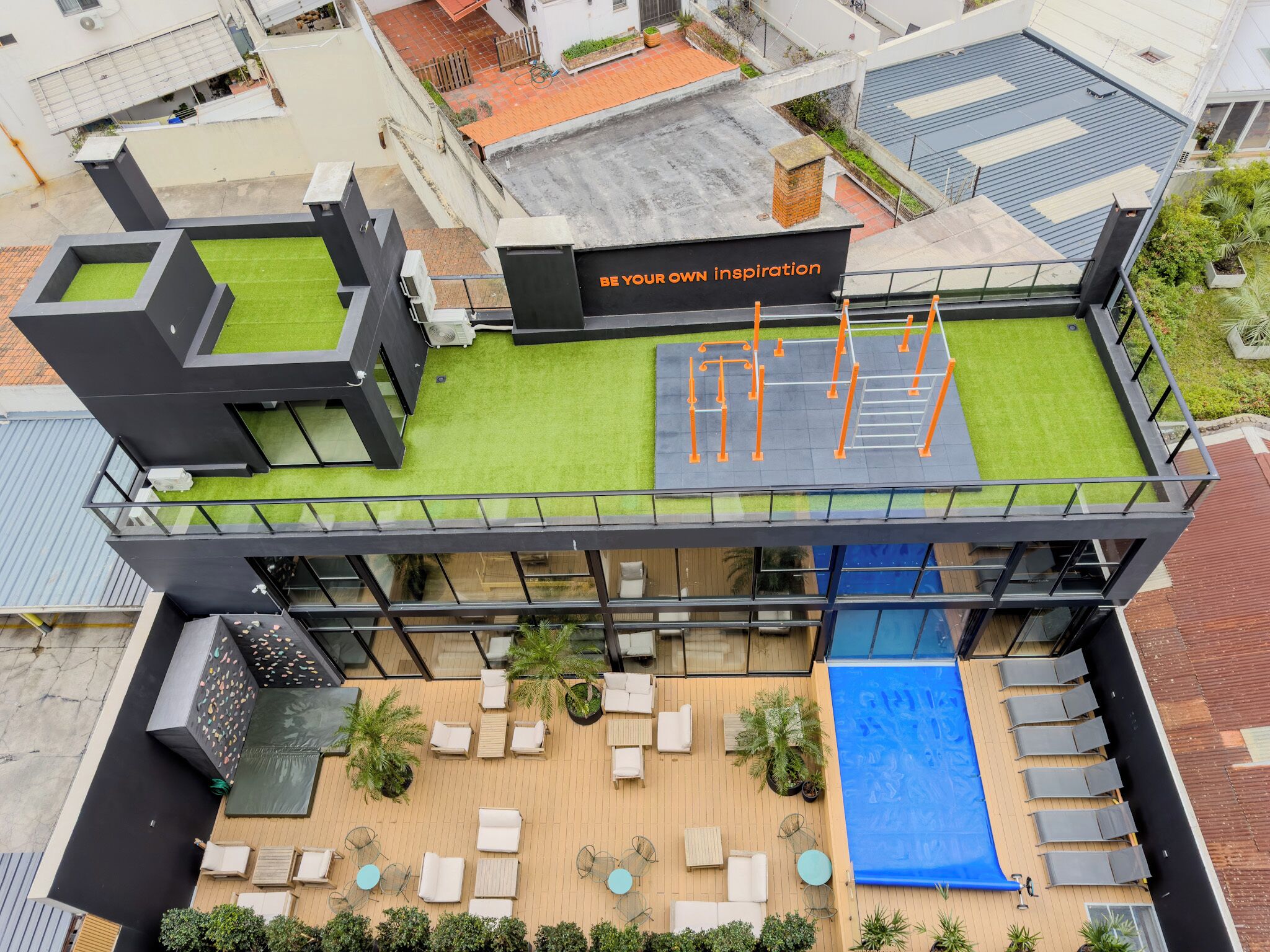 Eine Dachterrasse mit Rasenfläche, Gartenmöbeln und einer Kletterwand.