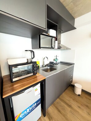 A compact kitchen with a microwave, toaster, sink, and a small refrigerator. - Modern WTC Studio Apartment | Gym + Pool (Montevideo)