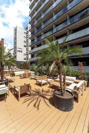 A rooftop terrace with outdoor seating and a palm tree.