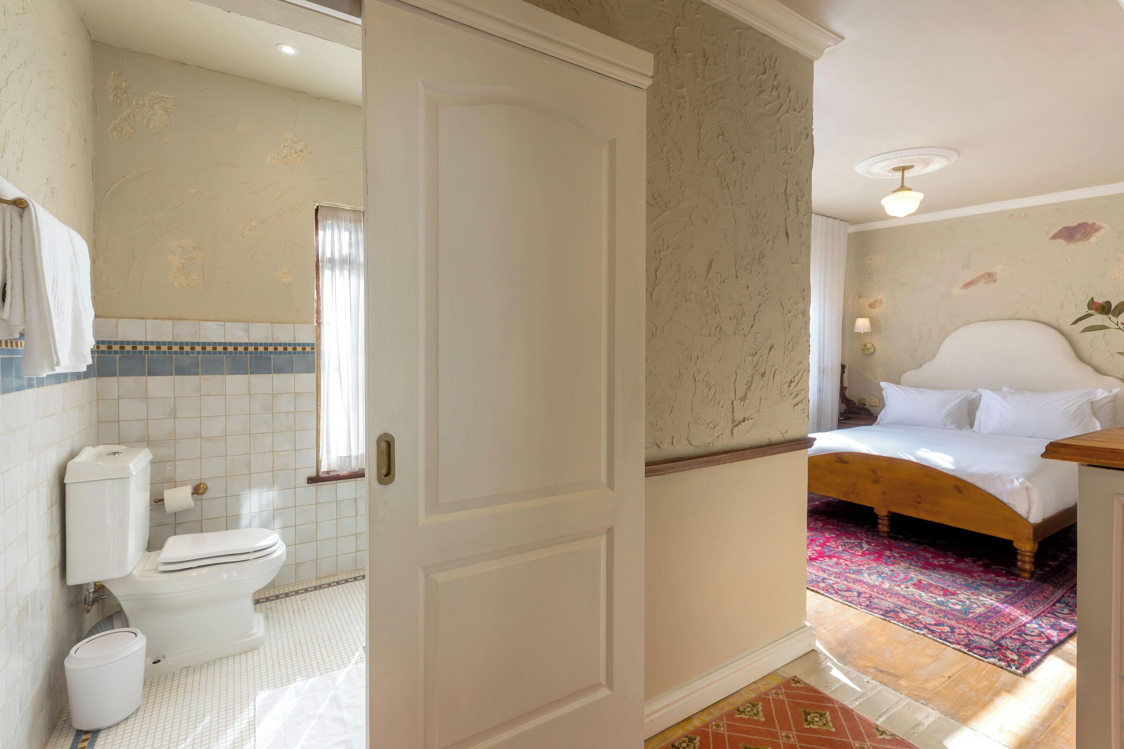 A hotel room with a bathroom, a bed, and a window.