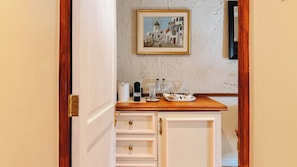 A hotel room with a wooden counter, a painting of a coastal scene, and a minibar. - Royva Bo-Kaap (Cape Town)