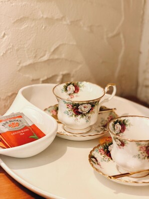 A tea set with floral patterns on cups and saucers, a teapot, and a tea bag. - Royva Bo-Kaap (Cape Town)