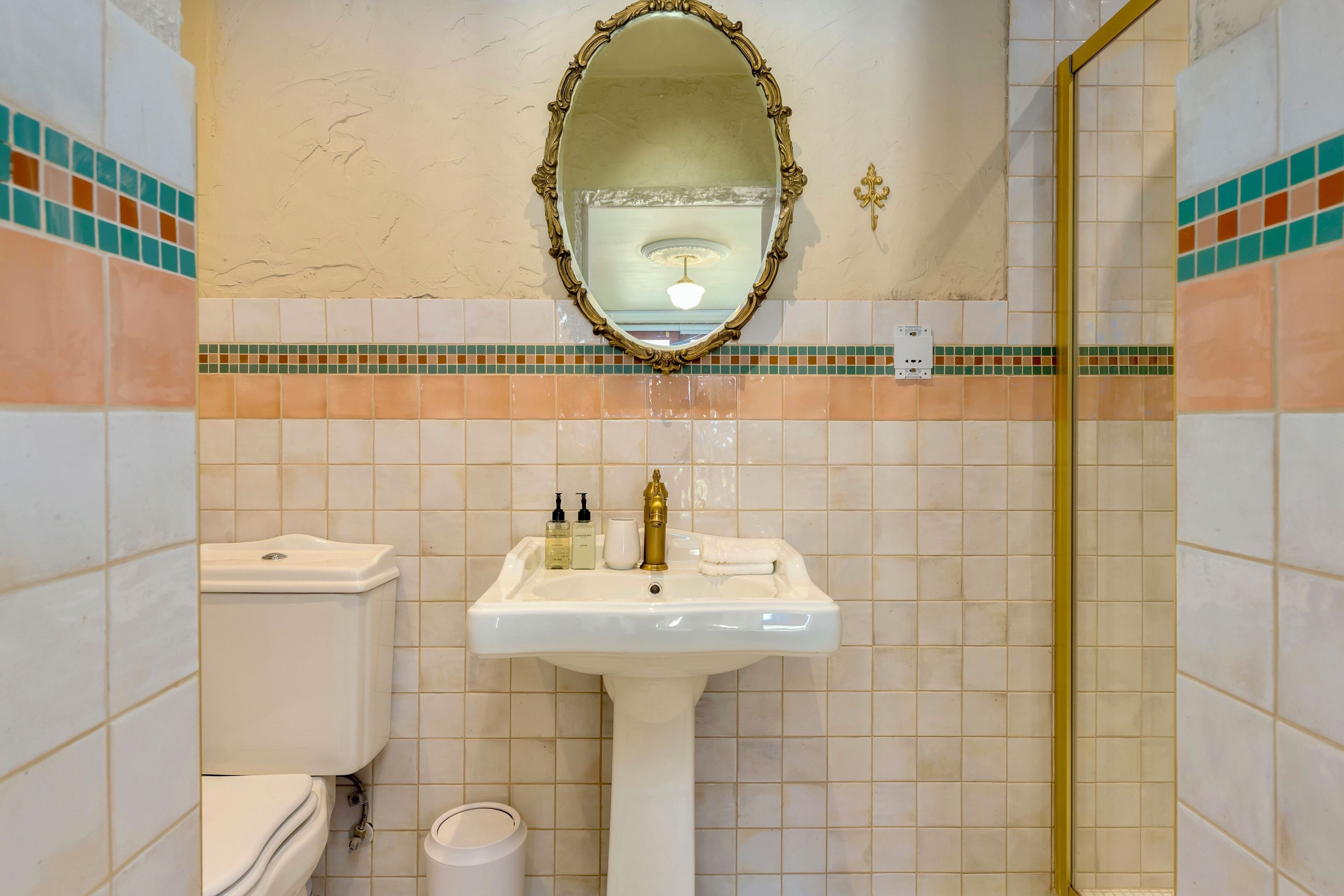 A bathroom with a white sink, a toilet, a mirror, and a shower.