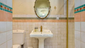 A bathroom with a white sink, a toilet, a mirror, and a shower.