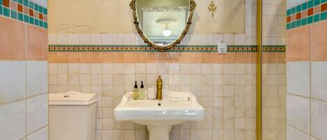 A bathroom with a white sink, a toilet, a mirror, and a shower.