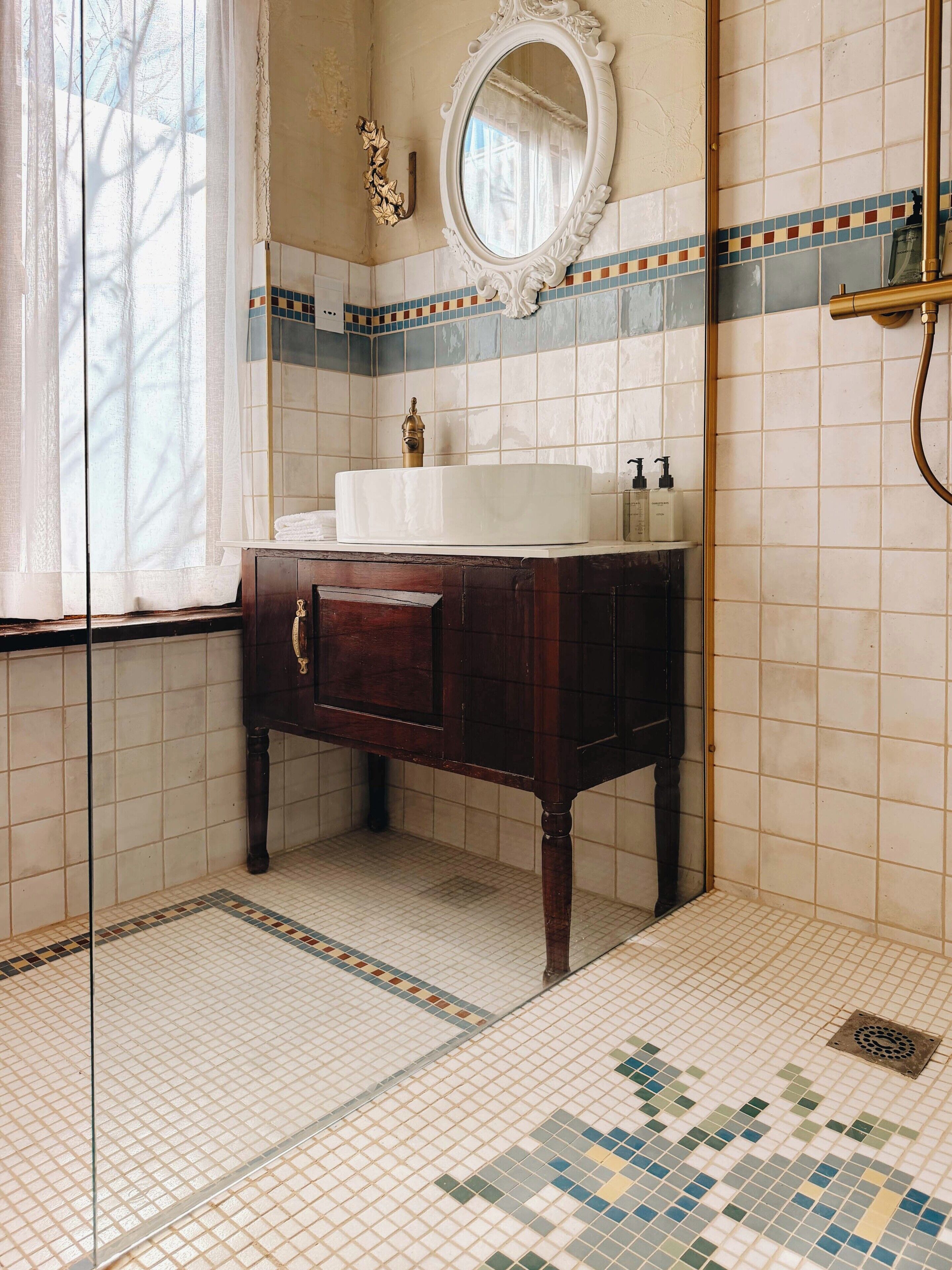A bathroom with a white sink, a mirror, and a shower.