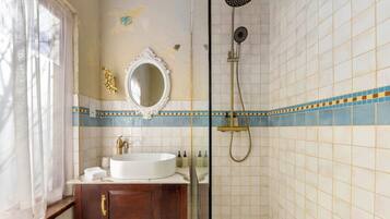 A bathroom with a white sink, wooden vanity, a mirror, and a shower.