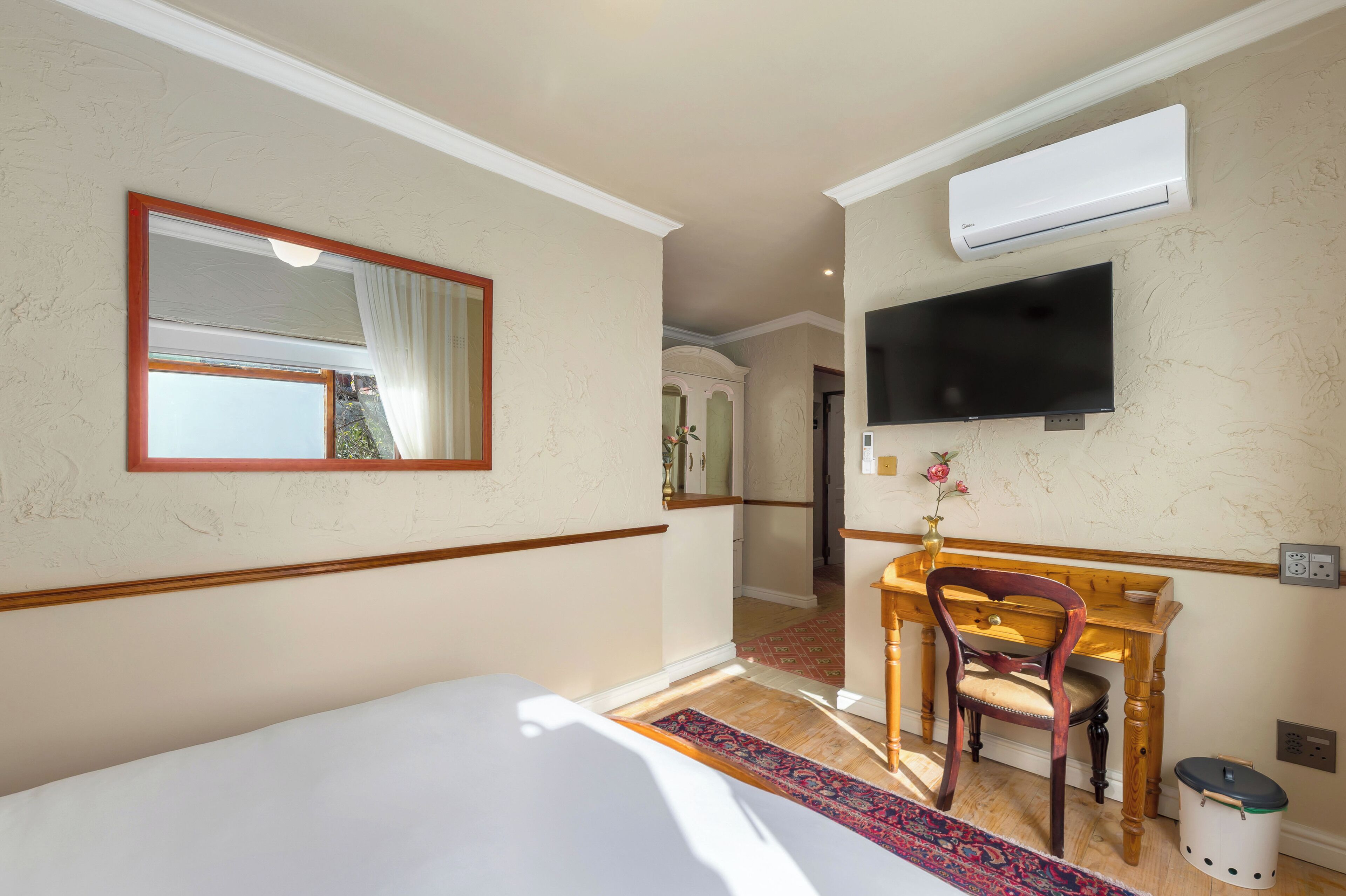 Ein Hotelzimmer mit einem Bett, einem Schreibtisch, einem Stuhl, einem Fernseher und einer Klimaanlage.