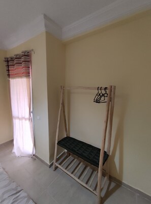 A room with a wooden bench against the wall, a window with curtains, and a tiled floor. - Marrakech Airport Highlights - 5 min (Marrakech)