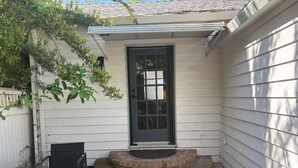 Ein Haus mit Eingangstür, einer kleinen Veranda und einer Bank.