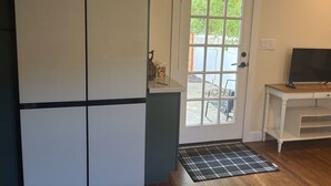 Ein Zimmer mit einer weißen Tür, einem Fernseher auf einem Holzboden und einem kleinen weißen Tisch.