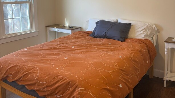 Ein Schlafzimmer mit einem Bett, einem Nachttisch, einem Deckenventilator und einer Klimaanlage.