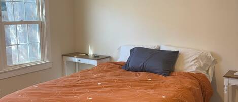 Un dormitorio con cama, mesita de noche, ventilador de techo y aire acondicionado.