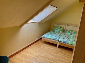 A small, single-bed room with a sloped ceiling and a skylight. - Gîte Ty an Aber sur l’Aber Benoit (Saint-Pabu)